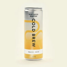 A straightforward product shot of a single 355-milliliter can of Pilot Coffee Roasters Black Cold Brew against a seamless light beige background. The can's design features a silver top fading into a yellow bottom with abstract curved lines.