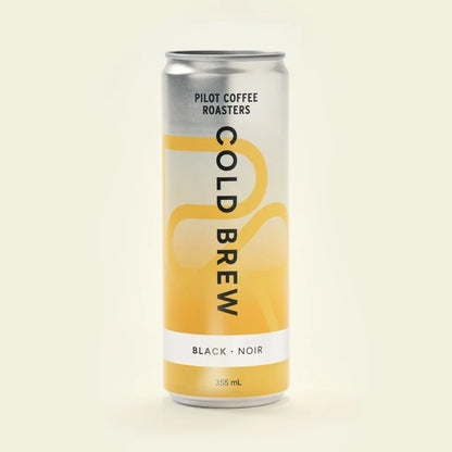 A straightforward product shot of a single 355-milliliter can of Pilot Coffee Roasters Black Cold Brew against a seamless light beige background. The can's design features a silver top fading into a yellow bottom with abstract curved lines.